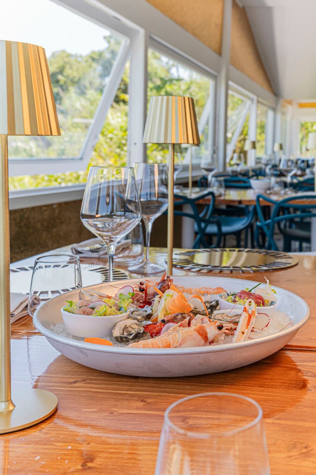 Plateau di crudi con ostriche, scampi e gamberi tra le lampade dorate della sala