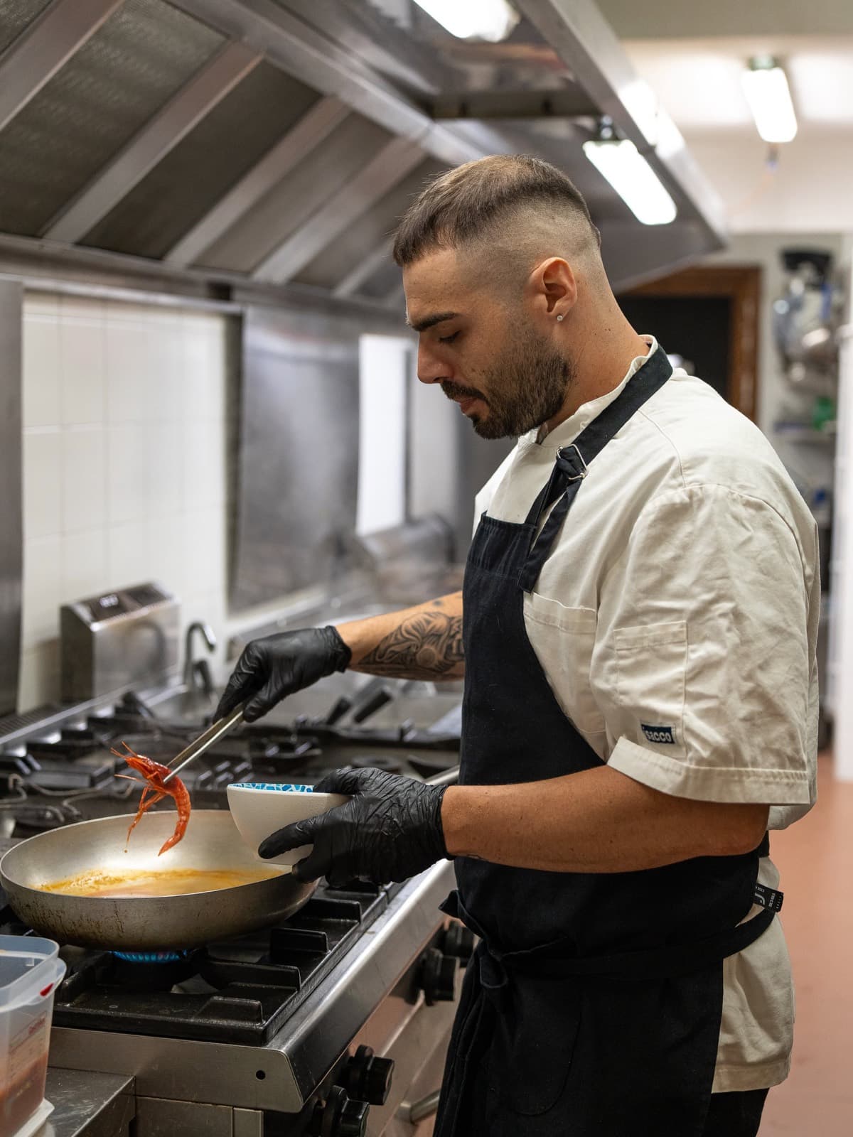 Lo chef in cucina impiatta un gambero rosso appena saltato in padella