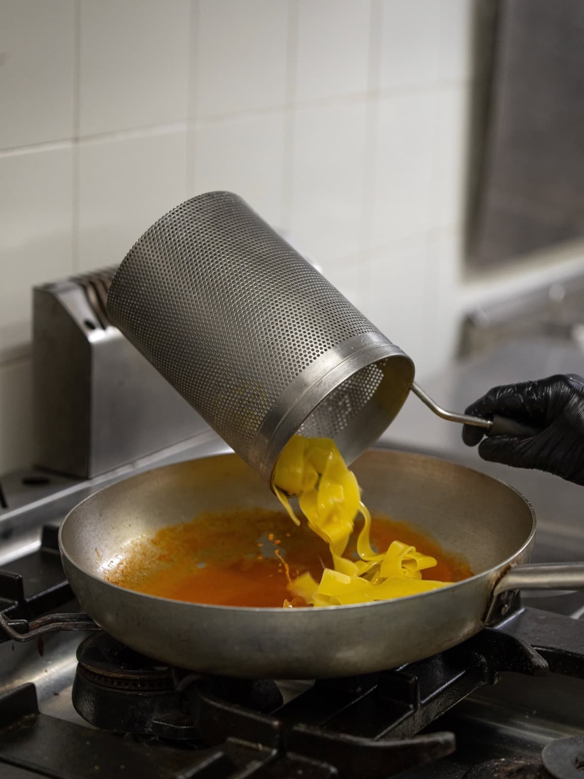Pappardelle appena scolate versate nella padella con il sugo di crostacei