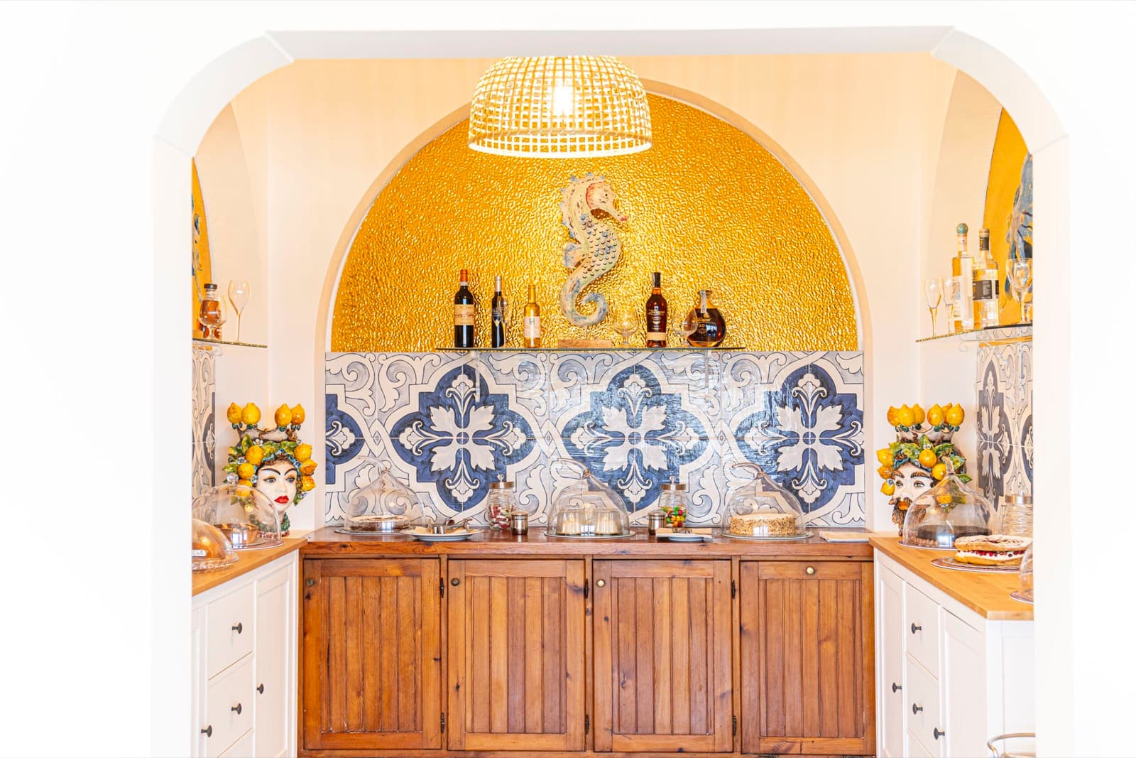 L'angolo bar con l'arco dorato, le maioliche blu e le teste di moro con i limoni
